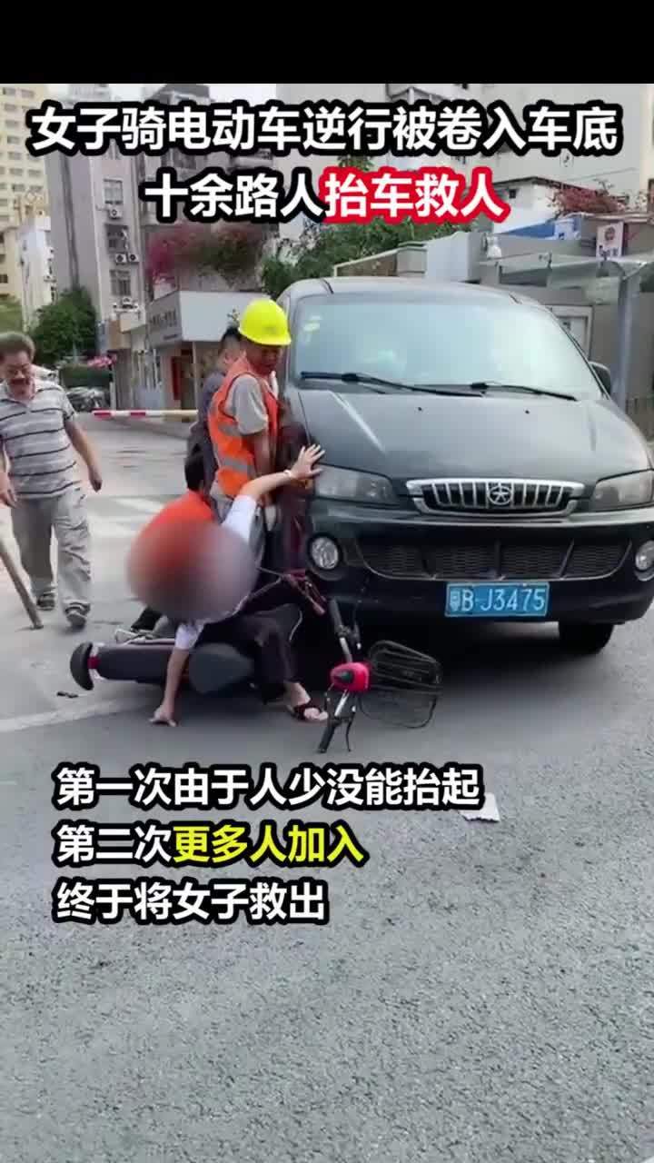 电瓶车被卷入车底众人抬车救人